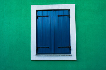 Blue window shutters on green wall - background wallpaper