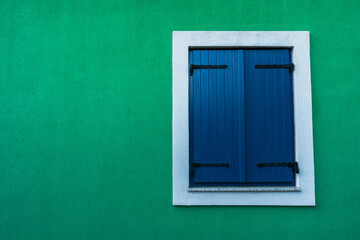 Blue window shutters on green wall - background wallpaper