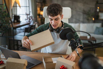 Young man open gift while record a podcast or stream at home studio