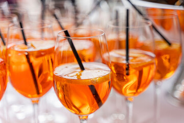 Glasses of refreshing Aperol spritz are displayed at a buffet at a wedding party