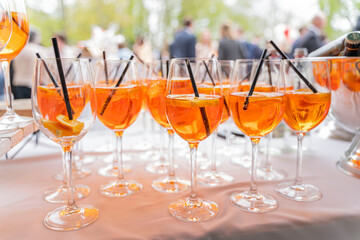 Glasses of refreshing Aperol spritz are displayed at a buffet at a wedding party