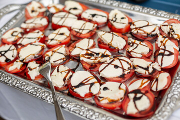 Fresh Caprese tomato and mozzarella with aceto di balsamico appetizer on a silver plate at a wedding party
