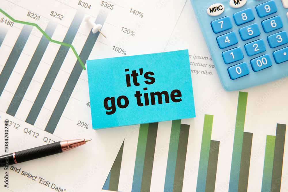Poster text it's go time on easel with office tools and paper