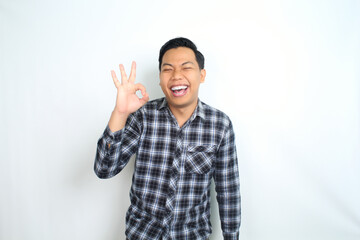 Fototapeta premium success asian man show okay signs using finger with laughing expression, accept and approved gesture, isolatd on white background, wear casual shirt