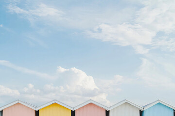 Fototapeta premium row of beach houses in mint, coral, yellow and blue, cirrus clouds in azure sky