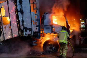 Firefighters spray water on fire in large cargo truck	