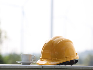Construction Break: A yellow hard hat rests beside a white coffee cup on a concrete surface,...