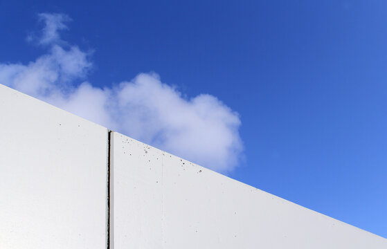 White concrete building wall against a blue sky with a cloud abstract textured background