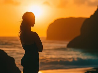 Silhouettes of a woman practicing yoga at sunset on the beach