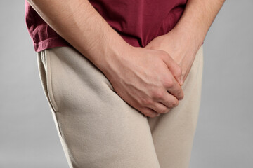 STD (sexually transmitted diseases). Man suffering from symptoms on grey background, closeup