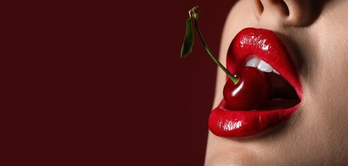 Beautiful sexy woman with red lips and cherry on dark background with space for text, closeup