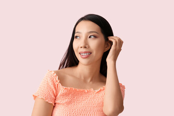 Portrait of pretty young Asian woman on pink background