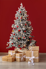 Decorated Christmas tree with presents near color wall