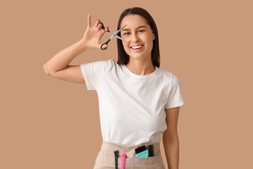 Female hairdresser with scissors on brown background