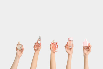Female hands with pink bottles of perfume on white background