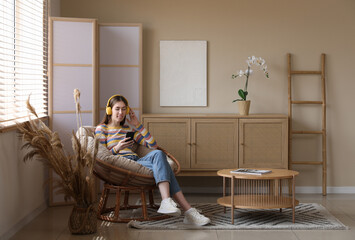 Young woman listing to music while sitting in armchair in room