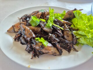 Deep fried sun-dried squid with special sauce serving on the plate. Famous seafood menu in Asian restaurant. 