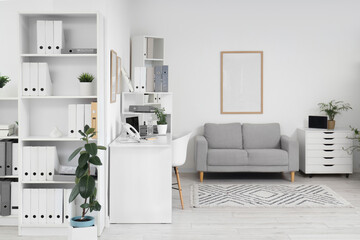 Interior of light office with workplace, sofa and shelf units