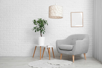 Armchair and coffee table with houseplant near white brick wall in room