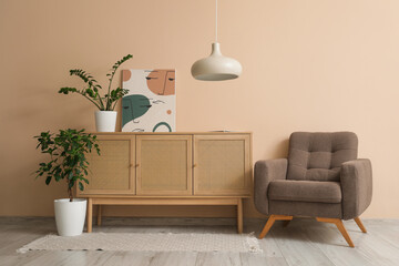 Armchair, chest of drawers, picture and houseplants in interior of living room