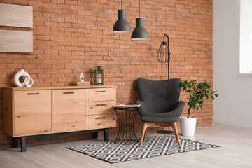 Armchair with footrest, coffee table, chest of drawers and lamps in room
