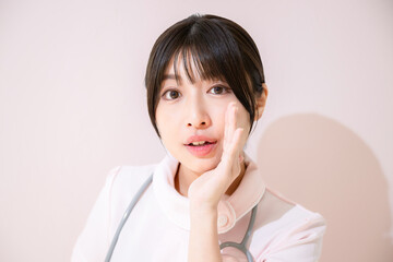 お～いと呼ぶ、内緒話をする看護師のクローズアップ　背景ピンク