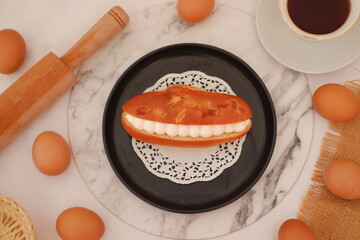 Eclair on a black plate with marble table