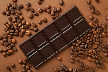 Tasty chocolate bar and coffee beans on brown background, flat lay