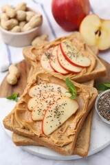 Tasty sandwiches with peanut butter, apple, chia seeds, nuts and mint on table, closeup