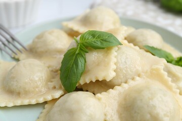 Delicious ravioli with cheese and basil served on plate, closeup