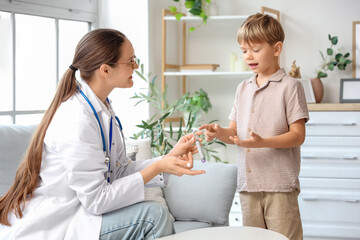 Obraz premium Female doctor showing lancet pen to little diabetic boy at home