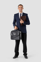 Handsome businessman in eyeglasses with notebook and briefcase on white background