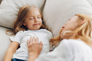 Mother and daughter embracing on a cozy couch, sharing a tender moment in a warmly lit living room