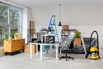 Interior of office with desk, boxes and vacuum cleaner on moving day