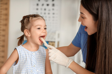 Female pediatrician checking cute little girl's throat in clinic