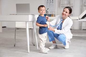 Female pediatrician with stethoscope listening to little boy in clinic