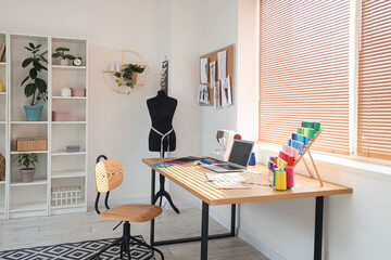 Interior of light atelier with tailor's workplace, shelf unit and mannequin