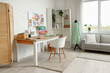 Interior of light atelier with tailor's workplace, sofa and mannequin