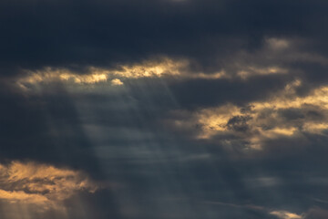 Sun rays through the clouds in the blue sky. Natural background.