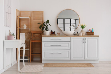 Interior of light bathroom with sink, mirror and wooden folding screen