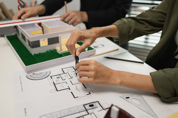 Architects work with engineers and contractors in the office to check the accuracy of the first draft plan, blueprint on the desk, three architects are working together in the workplace