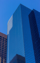 Naklejka premium A close-up view of modern office buildings in downtown Los Angeles. The buildings feature sleek glass facades that reflect the surrounding structures, creating an intricate pattern of reflections.