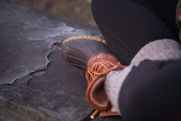 Naklejka premium A close-up of winter boots resting on a stone surface during a chilly afternoon, highlighting the cozy fabrics and sturdy design in a natural outdoor setting