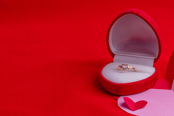 ring box with diamonds on a hand-cut paper heart on a red background