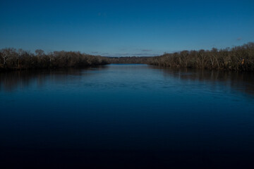 Tranquil river landscape under a clear blue sky captured during late afternoon hours in a serene natural setting