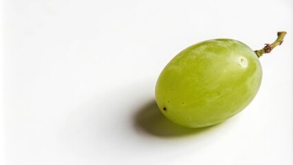 Obraz premium A single, ripe green grape rests on a pristine white surface, showcasing its vibrant color and subtle texture.
