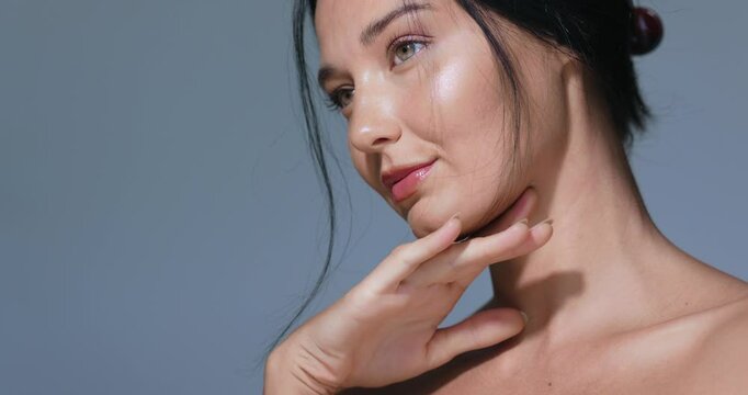 Portrait of an elegant woman with hydrated skin and a graceful hand pose against a blue background. Perfect for beauty, skincare, and cosmetics advertisements and high-quality promotional materials.