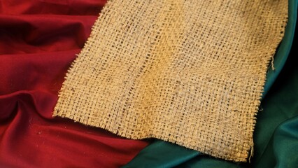 A rustic woven vintage burlap featuring green and red plain fabric, copy space for minimalist...