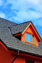 Orange Brick House With Dark Roof And Dormer Window
