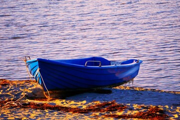Łódź rybacka na wybrzeżu. Niebieska łódź pozostawiona na plaży. © Adam